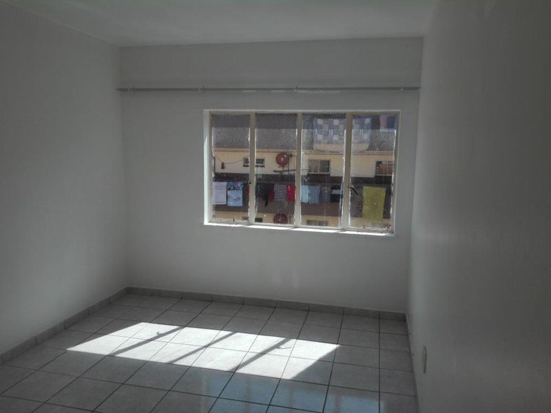 An empty bedroom featuring tiled flooring and a curtain rail, providing a blank canvas for personalization.