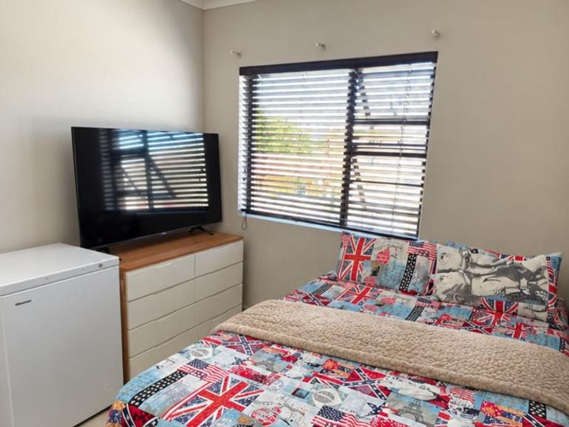 A functional bedroom featuring neutral wall tones, a window with fitted venetian blinds, and coving detail.