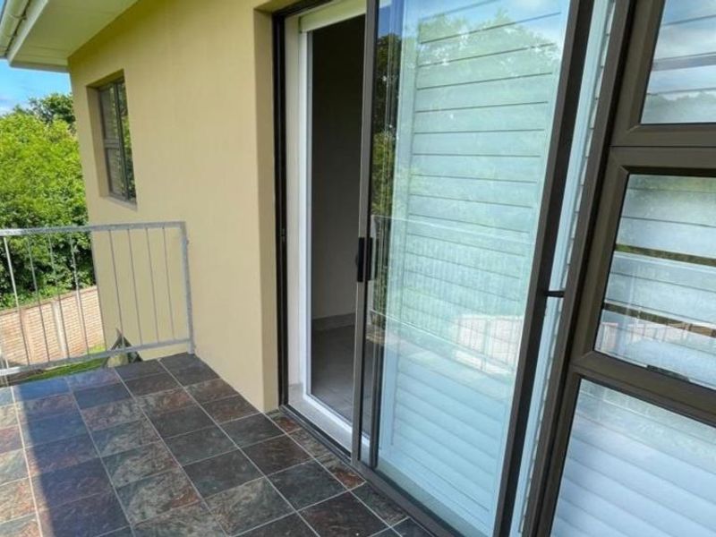 A private balcony featuring tiled flooring, a metal balustrade, and large sliding glass doors providing access to the interior.