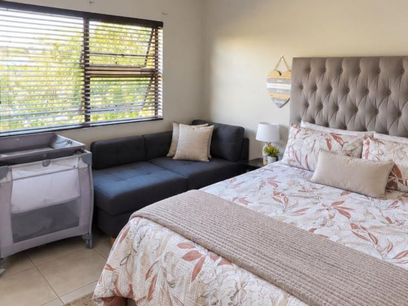 A well-maintained bedroom featuring neutral tiled flooring and venetian blinds, offering a comfortable and functional living space.