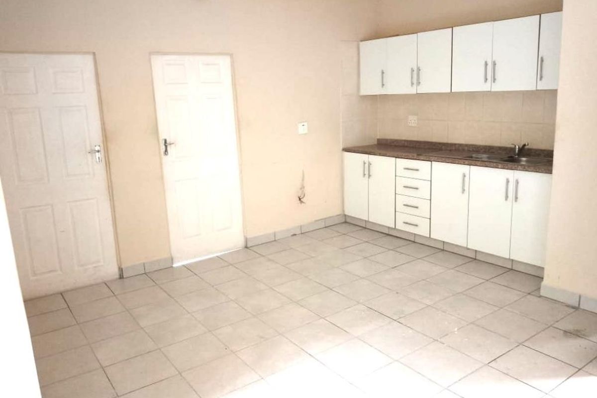 A functional kitchen area featuring white cabinetry, tiled flooring, and two internal doors, offering a blank canvas for potential renovation or modernization.