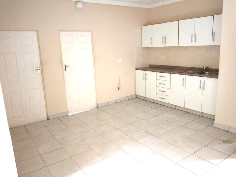 A functional kitchen area featuring white cabinetry, tiled flooring, and two internal doors, offering a blank canvas for potential renovation or modernization.