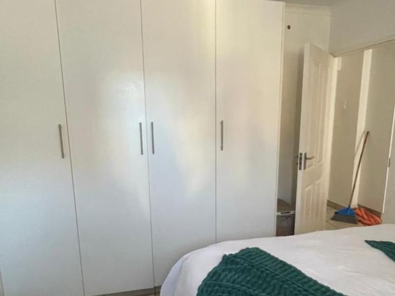 A bedroom featuring floor-to-ceiling built-in cupboards with white finish and modern handles, providing ample storage space.