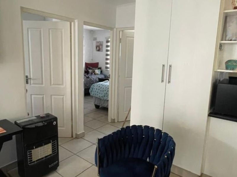 A functional hallway area featuring built-in storage cupboards and tiled flooring, providing access to adjacent bedrooms.