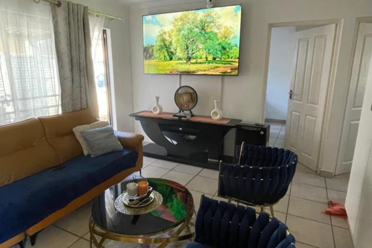 A living room featuring tiled flooring, natural light from a window, and access to adjacent rooms via internal doors.