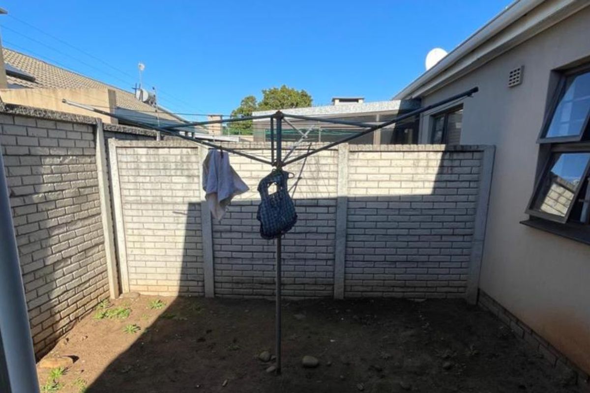 A private rear courtyard area featuring a brick boundary wall and a rotary clothesline, offering potential for landscaping or outdoor living space development.