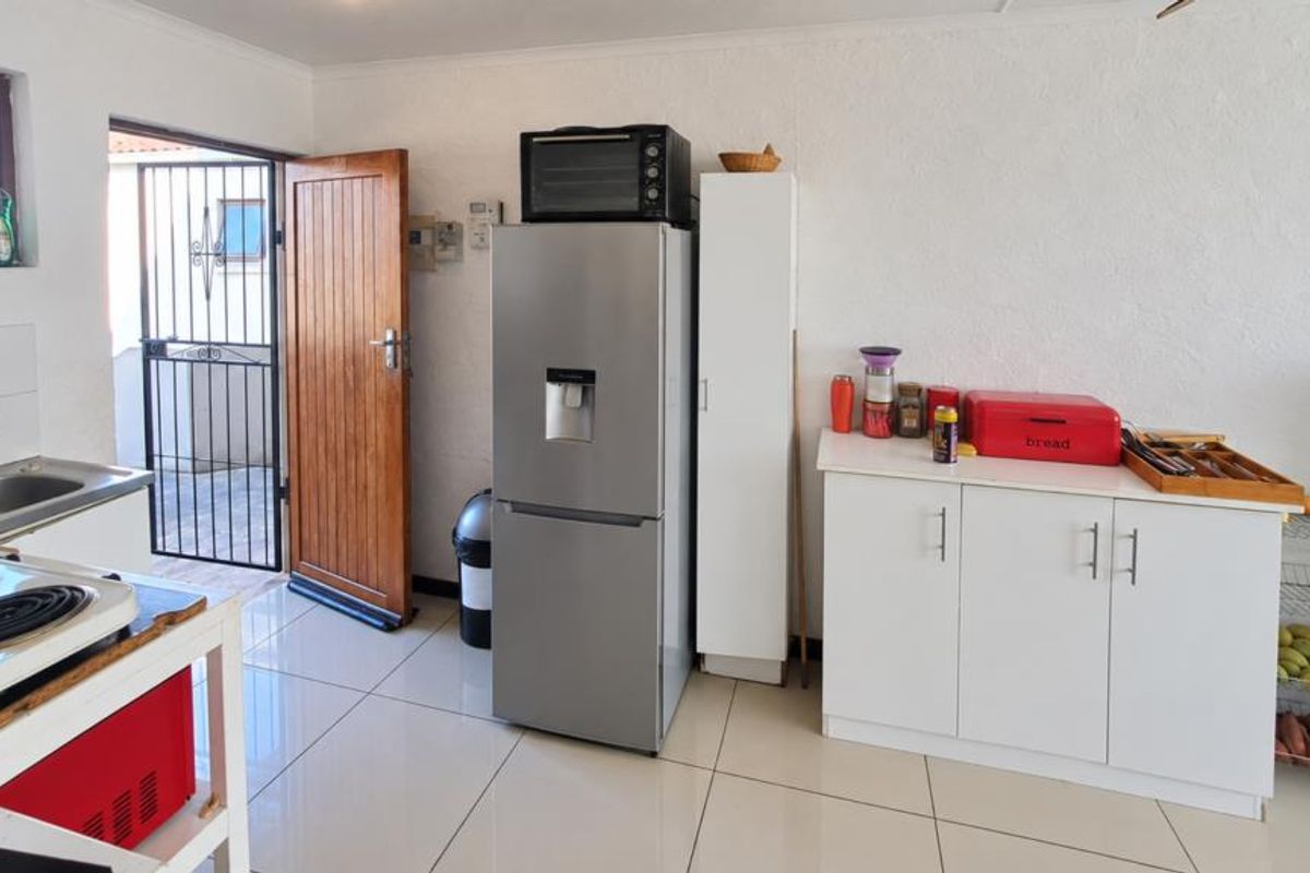 A functional kitchen area featuring tiled flooring, built-in cabinetry, a stainless steel sink, and direct access to an exterior security gate.