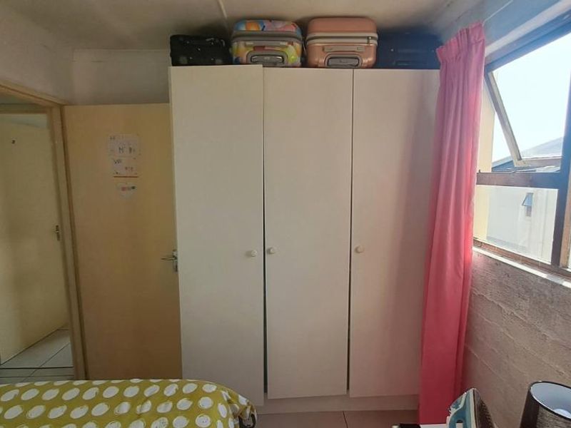 A bedroom featuring a built-in wardrobe and a large window providing natural light.