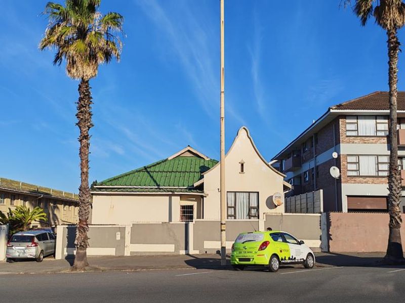 Front elevation of a residential apartment building featuring a gabled roof, boundary wall, and secure entrance area.