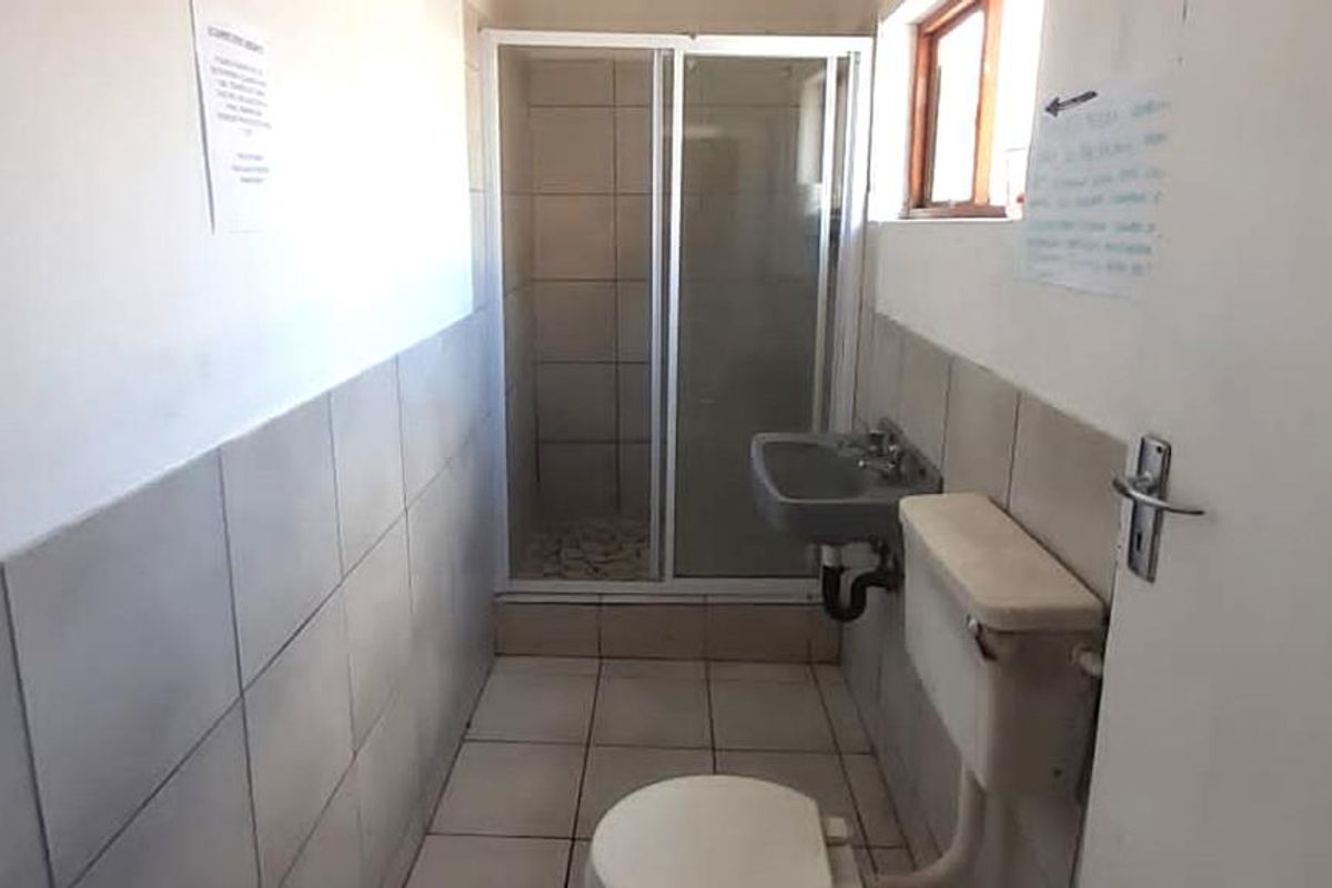 A compact, functional bathroom featuring a shower enclosure, wall-mounted basin, and toilet with tiled walls and flooring throughout.