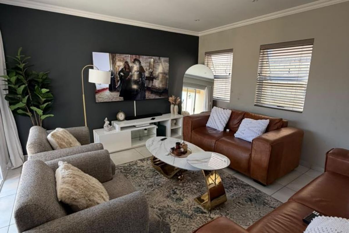 A well-maintained living room featuring tiled flooring, recessed downlighting, and a dark accent wall, creating a modern and comfortable atmosphere.