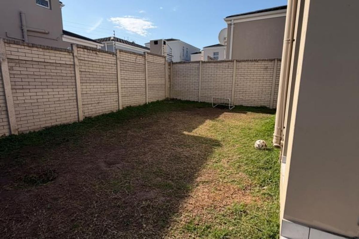 A private rear garden area featuring a brick boundary wall and tiled steps leading from the townhouse.