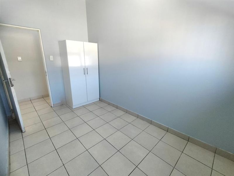 A simple, empty bedroom featuring neutral wall paint and light-colored floor tiles, providing a clean and versatile space ready for personalization.