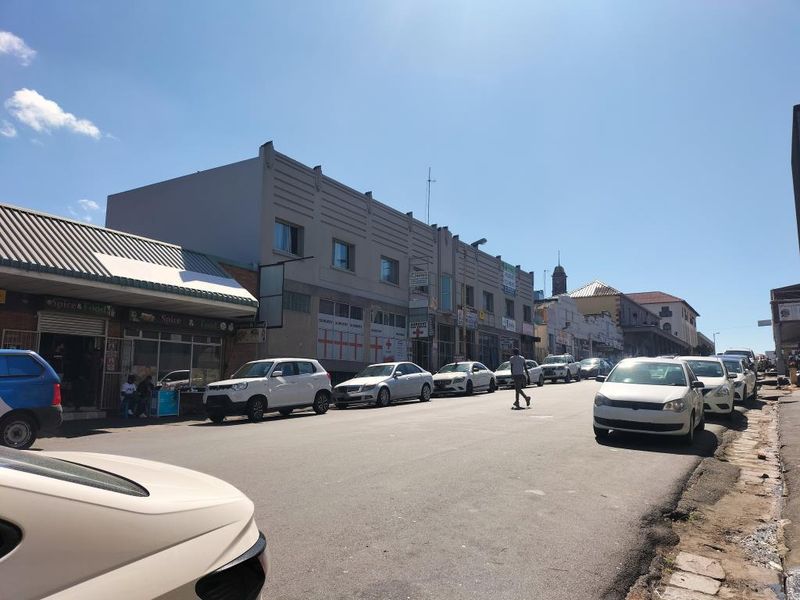 A street-level view of a commercial building facade featuring multiple storefronts along a busy urban road.