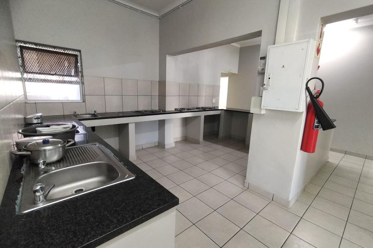 A functional kitchen area featuring tiled flooring, a built-in sink, and extensive countertop space, currently awaiting cabinetry installation or renovation.