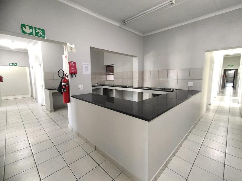 A functional, empty kitchen area featuring granite countertops, tiled flooring, and a tiled backsplash, suitable for commercial or residential utility use.