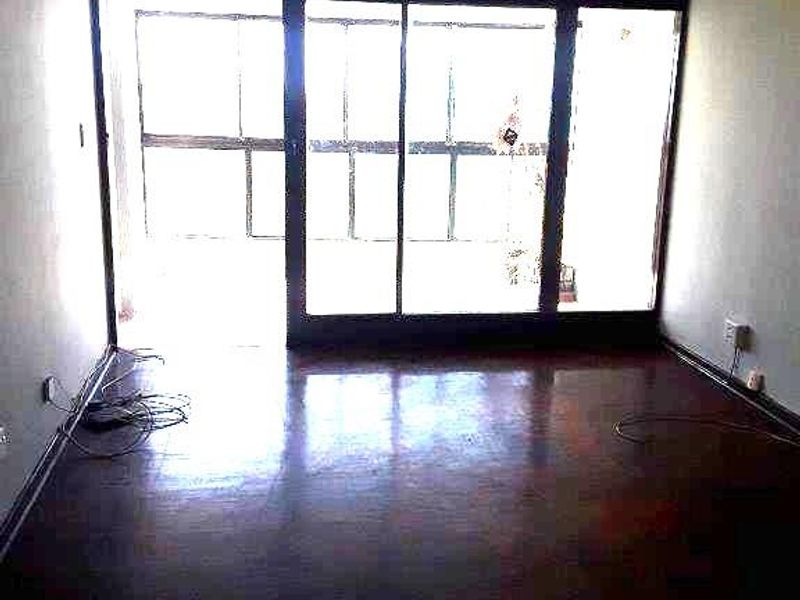 An empty living room featuring dark hardwood flooring and large sliding glass doors that provide ample natural light.
