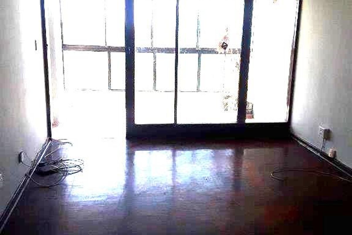An empty living room featuring dark hardwood flooring and large sliding glass doors that provide ample natural light.