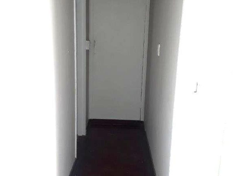 A narrow interior hallway featuring dark parquet flooring and a built-in storage cupboard, requiring minor cosmetic updates to refresh the space.