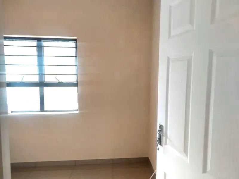 An empty bedroom featuring tiled flooring, a window with security bars, and a white panel door.