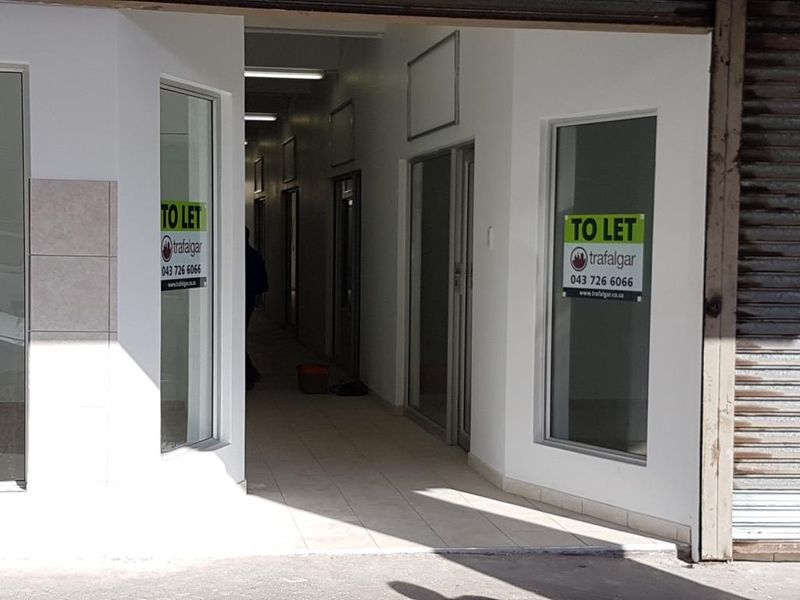 Commercial entrance area featuring tiled flooring, aluminium framed glass doors, and roller shutter security access.