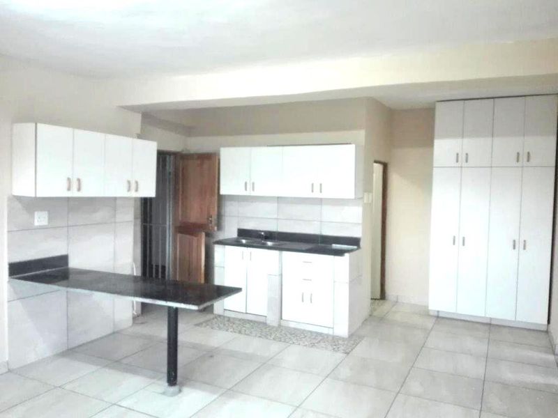 A functional kitchen featuring white cabinetry, dark stone countertops, a breakfast bar, and tiled flooring, offering a clean and practical layout.