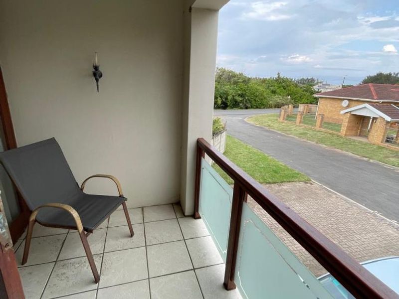 A covered balcony featuring tiled flooring and a glass and timber balustrade, offering an elevated view of the surrounding neighbourhood.