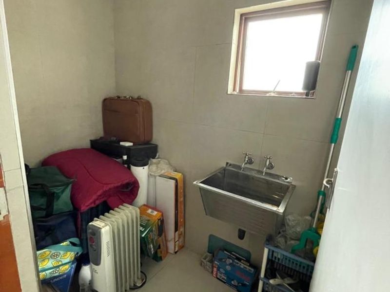 A functional laundry area featuring a stainless steel utility sink, tiled walls, and tiled flooring, providing a practical space for household tasks.