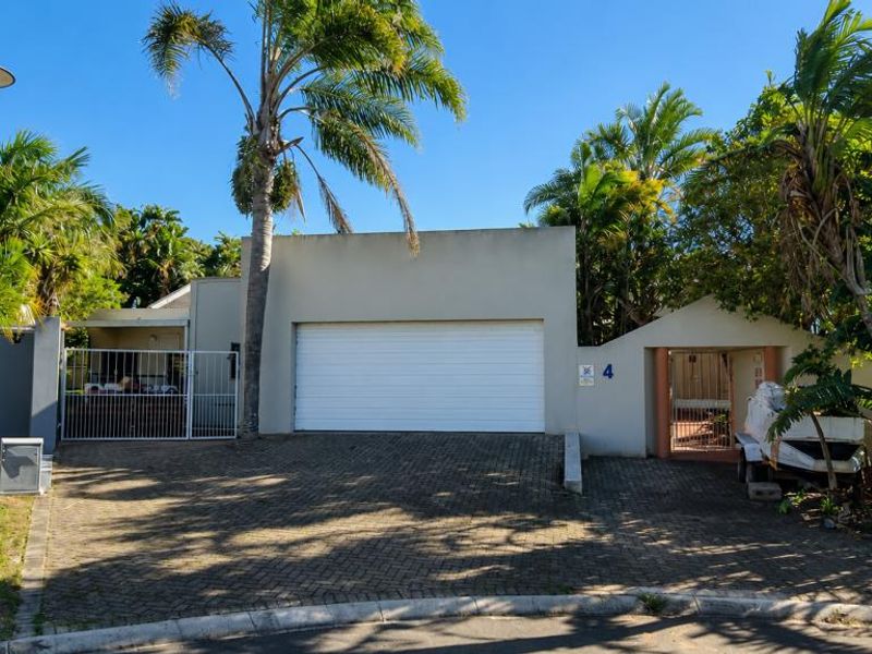 Front elevation of the property featuring a paved driveway, automated garage door, and secure pedestrian gate access.