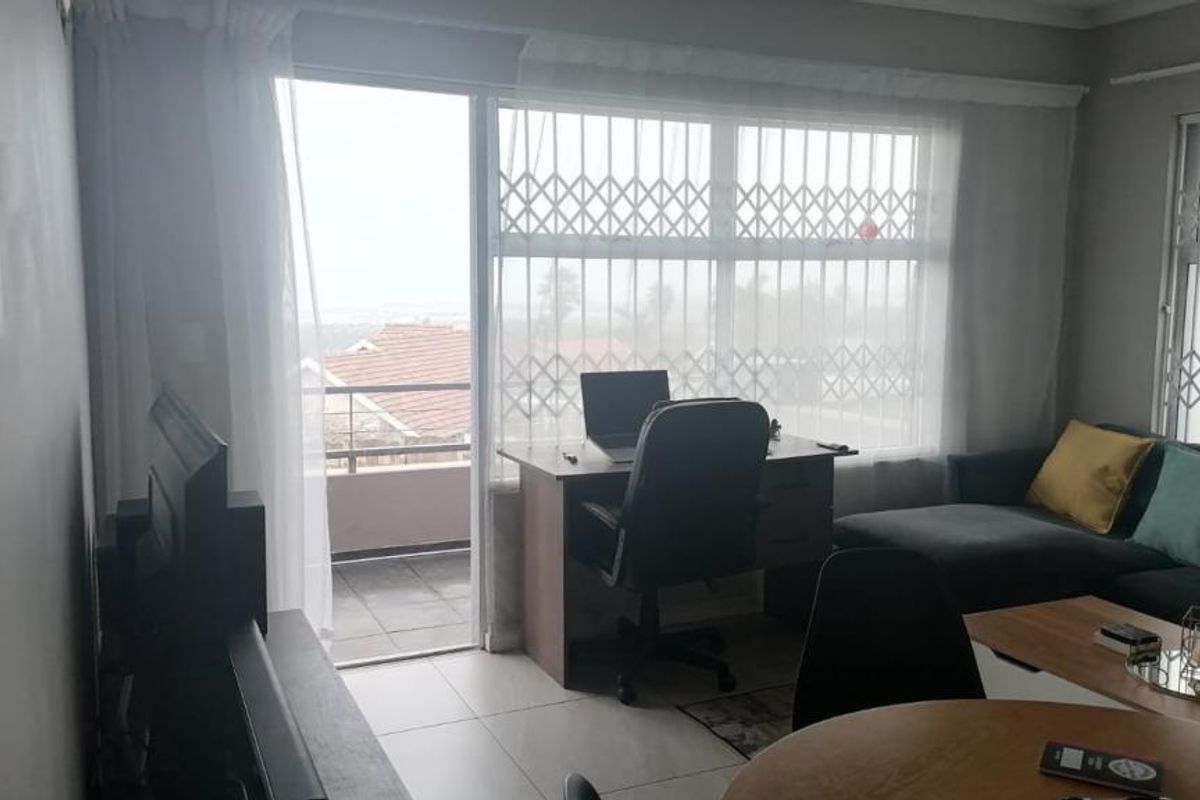 A living room featuring tiled flooring, large windows with security gates, and direct access to an outdoor balcony area.