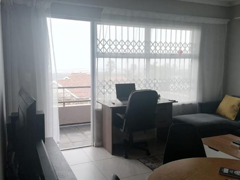 A living room featuring tiled flooring, large windows with security gates, and direct access to an outdoor balcony area.