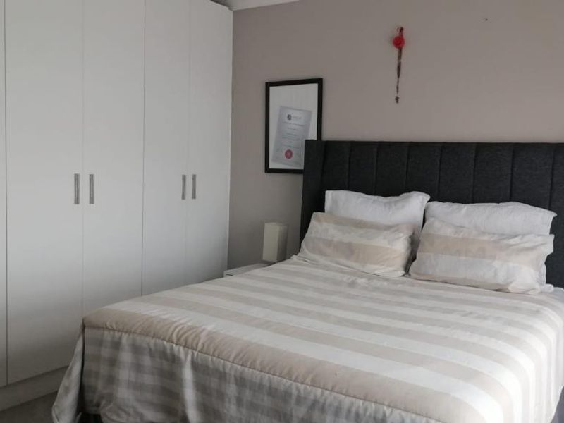 A well-maintained bedroom featuring neutral wall tones and ample built-in cupboard storage space.