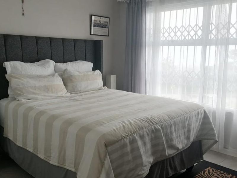 A well-maintained bedroom featuring tiled flooring and a large window fitted with a security gate for added safety.