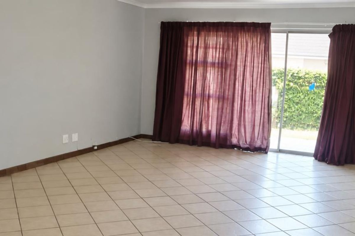 Spacious, empty living room featuring neutral wall paint, ceramic tile flooring, and a large sliding glass door providing access to the outdoor area.