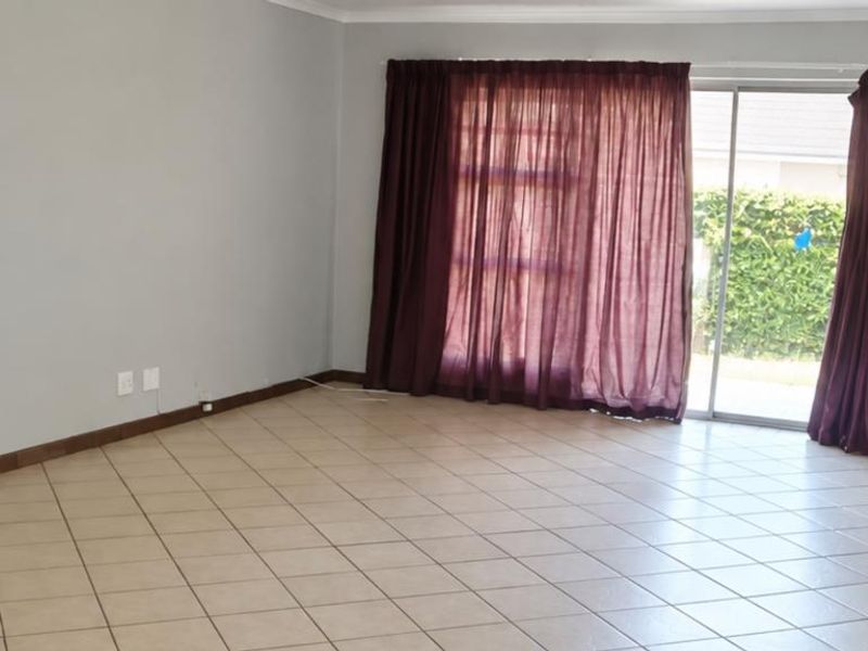Spacious, empty living room featuring neutral wall paint, ceramic tile flooring, and a large sliding glass door providing access to the outdoor area.