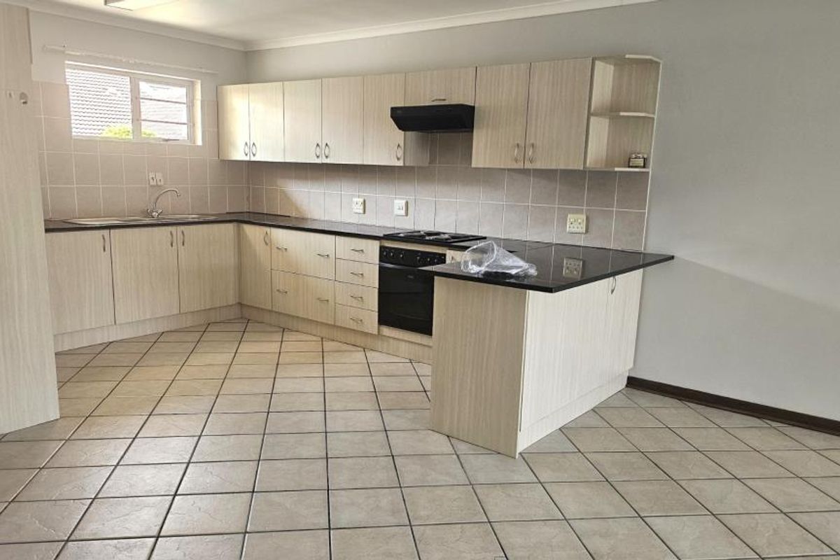 A clean, functional kitchen featuring light wood-finish cabinetry, dark countertops, tiled backsplash, and ceramic floor tiles, offering a neutral space ready for personalization.