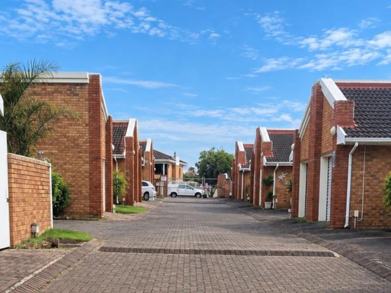 A view of the townhouse complex driveway featuring brick facades, tiled roofs, and paved access paths between the residential units.