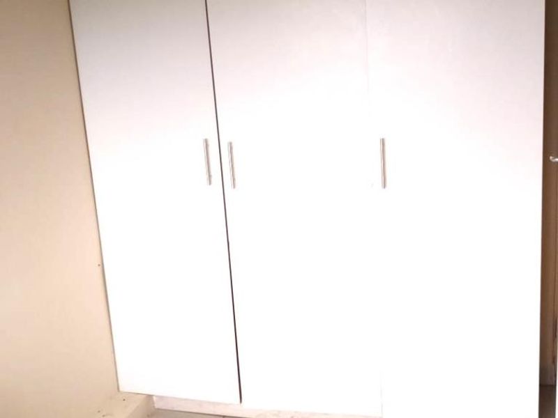 A bedroom featuring built-in white cabinetry and tiled flooring.