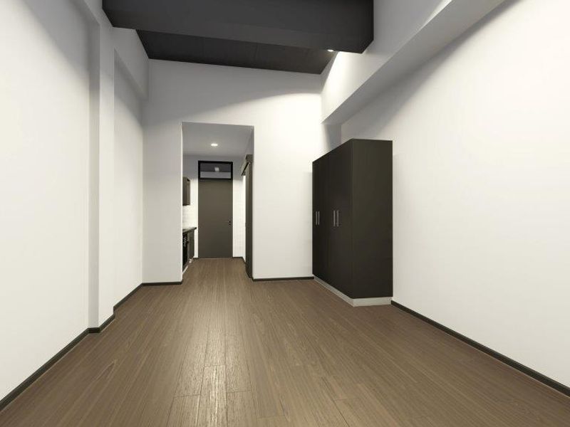 A modern, minimalist living area featuring dark wood-tone flooring, clean white walls, and built-in storage cabinetry with a contrasting dark ceiling detail.