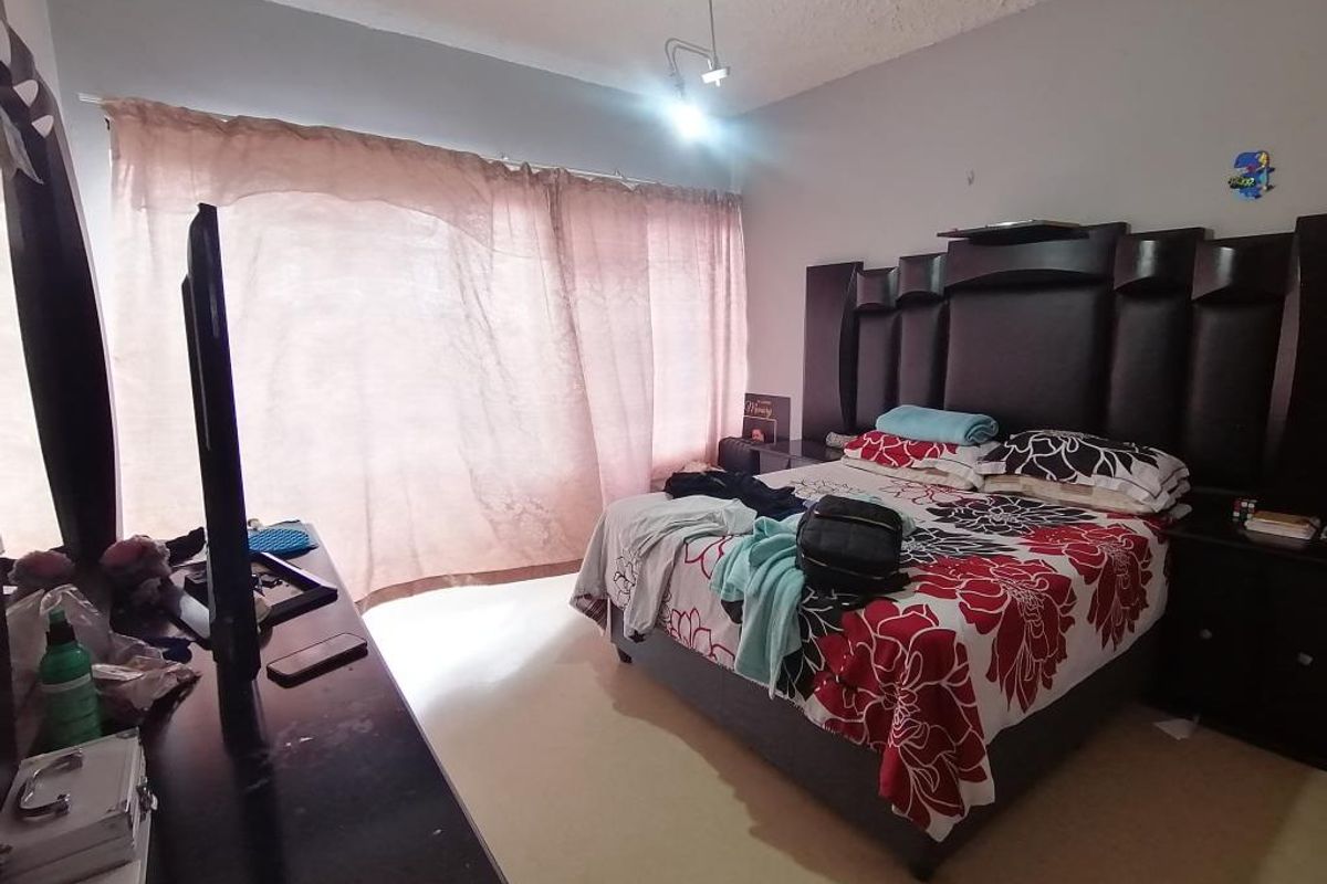 A bedroom featuring a textured ceiling and large window with curtain tracks, requiring cosmetic updates to improve the overall finish and appeal.
