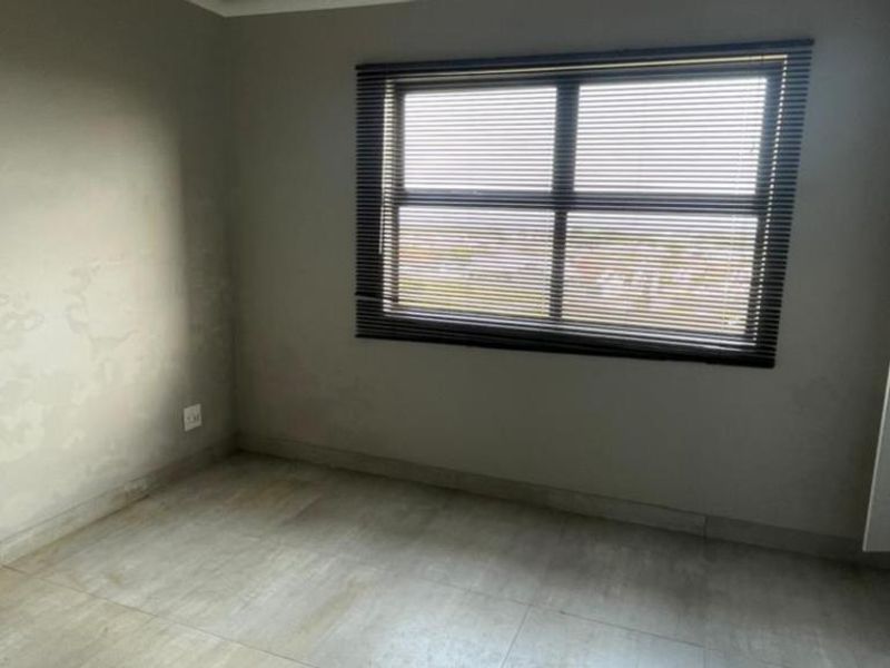 An empty bedroom featuring tiled flooring, built-in cupboards, and venetian blinds, requiring minor wall repairs and repainting to refresh the space.