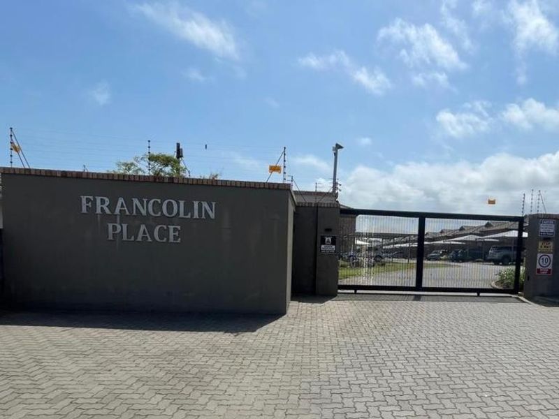 The entrance to Francolin Place townhouse complex, featuring a secure gated access point, paved driveway, and perimeter electric fencing.