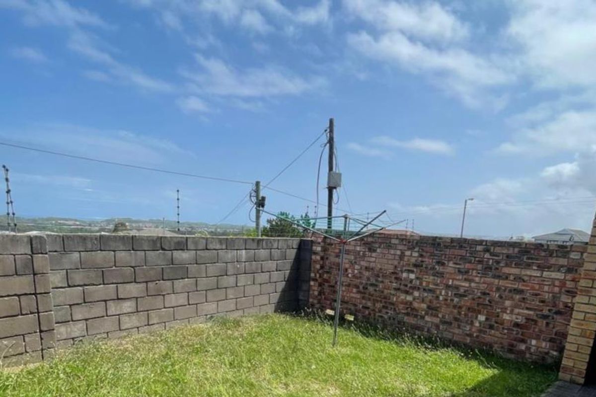 Rear garden area featuring a built-in brick braai, perimeter brick walling, and electric fencing, offering potential for outdoor landscaping and entertainment space.