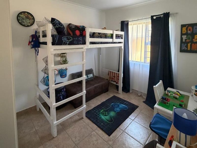 A clean, empty bedroom featuring neutral tiled flooring and white built-in cupboards, offering a blank canvas for personalization.