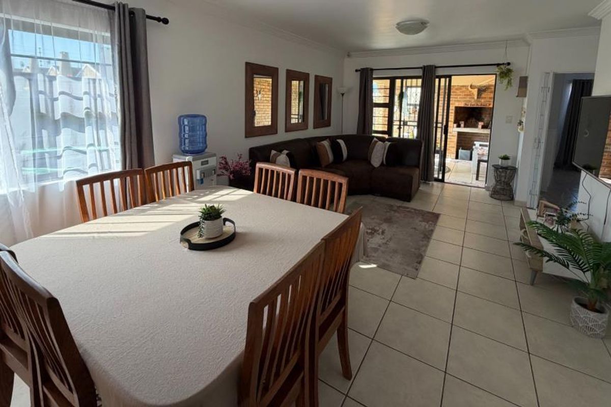 Spacious, tiled living area featuring a sliding security gate and glass door leading to an outdoor patio area.
