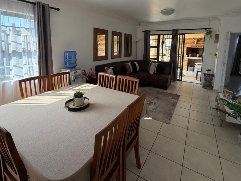 Spacious, tiled living area featuring a sliding security gate and glass door leading to an outdoor patio area.