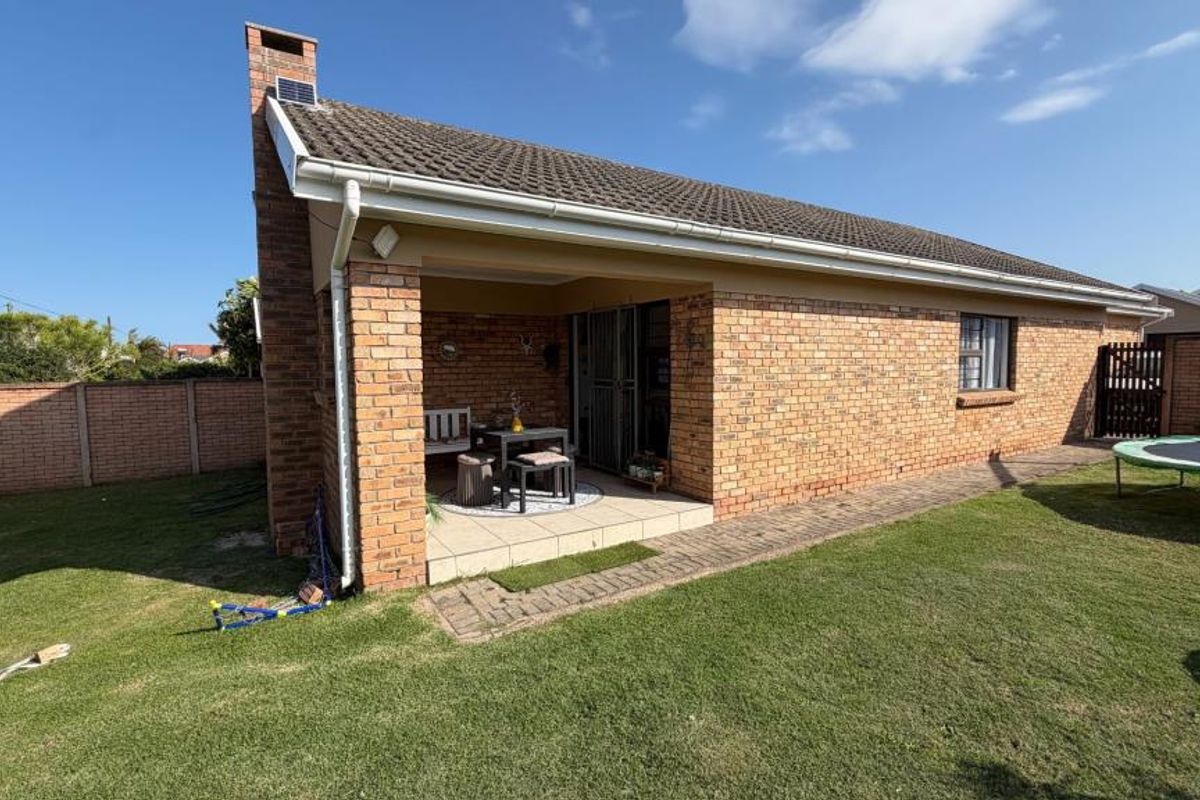 A private rear garden featuring a well-maintained lawn enclosed by brick boundary walls with integrated electric fencing.