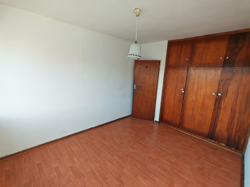 An empty bedroom featuring laminate flooring and built-in wooden cupboards, offering a blank canvas for personalization.