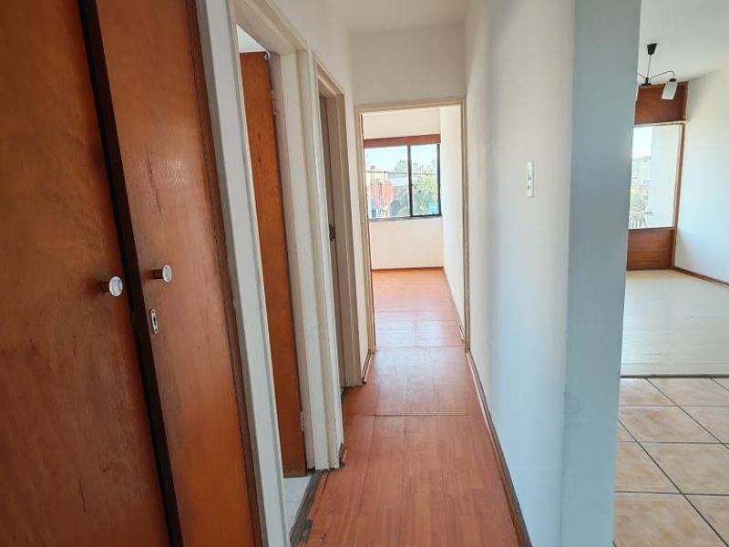 A functional hallway featuring built-in wooden cupboards and laminate flooring, providing access to adjacent living areas and bedrooms.