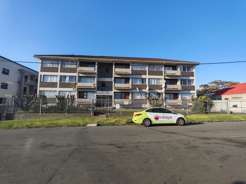 Front elevation of a multi-story apartment complex featuring brick cladding, private balconies, and secure perimeter fencing.